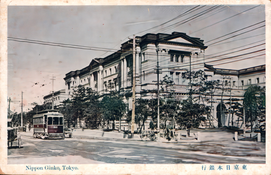 This coloured card shows a large bank building beside a street with a tram: On the card is printed “Nippon Ginko, Tokyo. The Japanese translates as “Bank of Japan, Tokyo.”