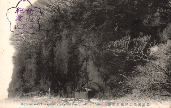 This black-and-white card shows a wooded rock face with small shrine structures at its base: On the card is printed “Biyobu-Iwa (The spreen-rocks) on the top of mt, Unzen. The Japanese is written partly in the older right-to-left direction. Read normally, it translates as:
温泉岳頂上屏風岩の景 — “View of Byōbu Rock at the summit of Mount Unzen.”
登山紀念 — “Commemoration of the mountain ascent.”
雲仙岳 — “Mount Unzen.”