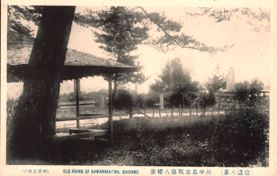This black-and-white card shows a tree-shaded pavilion and stone monument in a garden: On the card is printed “（版店書原河） OLD RUINS OF KAWANAKAJIMA, SHINANO.
The Japanese is printed in the older right-to-left direction:
河原書店版 — “Kawahara Bookshop edition.”
川中島古戰場八幡原 — “Hachimanbara, the old battlefield of Kawanakajima.”
信濃八景 — “Eight Views of Shinano.”