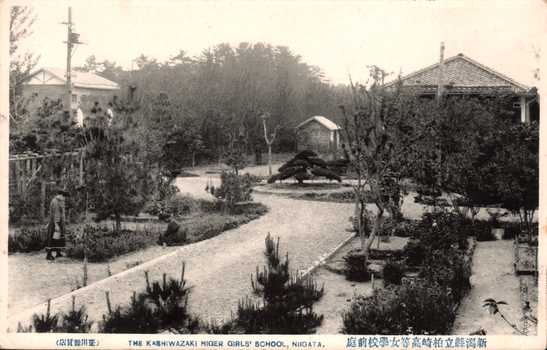 This black-and-white card shows a landscaped school garden with paths, trees and buildings: On the card is printed “（店眞寫川正） THE KASHIWAZAKI MIGER GIRLS' SCHOOL, NIIGATA. The Japanese is printed in the older right-to-left direction:
新潟縣立柏崎高等女學校前庭 — “Front garden of Niigata Prefectural Kashiwazaki Higher Girls’ School.”
正川寫眞店 — “Masakawa Photographic Shop.”