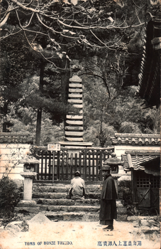 This black-and-white card shows a stone tomb monument behind a fence at the top of steps: On the card is printed “TOMB OF BONZE TOKUDO.
The Japanese is printed in the older right-to-left direction. Read normally, 開山德道上人御實墓 translates as “The actual tomb of the founding priest, the Venerable Tokudō.”