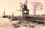 This black-and-white card shows small boats beside a harbour pier with a crane and a steamship. On the card is printed “(73) Plank road of Harbor at Osaka. The Japanese is printed from right to left and reads: 十（大阪百景）築港大桟橋」 — “No. 10, the Great Pier at Osaka Harbour (One Hundred Views of Osaka).”