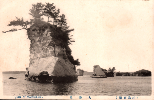 This black-and-white card shows a tall rocky islet topped with pine trees, with a sailing boat and smaller islands in the distance. On the card is printed “View of Matsushima”. The Japanese is printed from right to left and reads:（松島百景）大掛島」 — “Ōgake Island (One Hundred Views of Matsushima).”