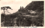 This black-and-white card shows two men seated on a large rock outcrop in a wooded mountain landscape. On the card is printed “The Nakanotake, myōgi Mountain.）”. The Japanese is printed from right to left and reads:
（妙義山名所）中ノ嶽大砲岩」 — “Cannon Rock at Nakanotake, a famous sight of Mount Myōgi.”