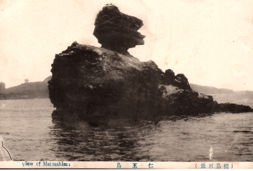 11731.094 This black-and-white card shows a large rock formation rising from the sea. On the card is printed “view of Matsushima”. The Japanese is printed from right to left and reads 仁王島（松島百景）, translating as “Niō Island (One Hundred Views of Matsushima).”