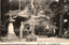This black-and-white card shows a small temple building among trees. On the card is printed “THE BENTEN TEMPLE OF RINSENJI”. The Japanese is printed from right to left and reads 臨川寺境内の辨天堂, translating as “Benten Hall in the grounds of Rinsenji Temple.” The clearest wording on the vertical sign appears to be: 大開帳紀念 — “Commemoration of the grand unveiling of a sacred image” It also includes: 五月廿四日 — “24 May” The remaining characters are too blurred and partly obscured to transcribe reliably.