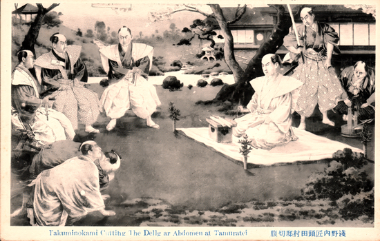 This black-and-white card shows a Japanese samurai seated on a mat during a ceremonial abdomen-cutting scene, surrounded by attendants in a garden. On the card is printed “Takuminokami Cutting The Belly or Abdomen at Tamuratei” The Japanese is printed in the traditional right-to-left direction. Read in modern order, it is:
浅野内匠頭田村邸切腹 English translation: “Asano Takumi-no-kami committing seppuku at the Tamura residence.