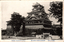 This black-and-white card shows a large traditional Japanese castle complex. On the card is printed “FORMER TKUMAMOTO-CASTLE.” The Japanese is printed right-to-left. Read in modern order, it is:（熊本名勝）西南役以前の熊本城 English translation: “(Famous view of Kumamoto) Kumamoto Castle before the Satsuma Rebellion.”
