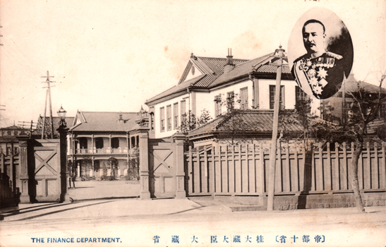This black-and-white card shows the entrance and buildings of a government department, with an inset portrait of a uniformed man. On the card is printed “THE FINANCE DEPARTMENT.” The Japanese is printed right-to-left. Read in modern order, it is:（帝都十省）桂大藏大臣　大藏省 English translation: “(Ten Ministries of the Imperial Capital) Finance Minister Katsura — Ministry of Finance.” 大藏省 — “Ministry of Finance” 桂大藏大臣 — “Finance Minister Katsura” 帝都十省 — “Ten Ministries of the Imperial Capital”