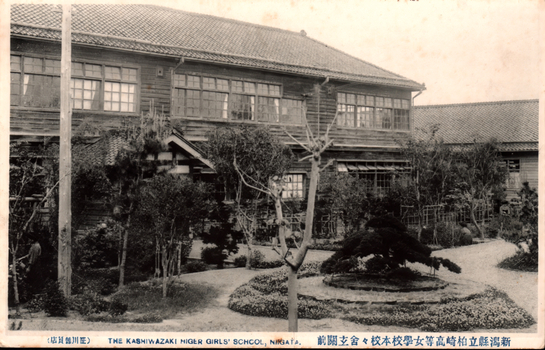 This black-and-white card shows a large Japanese school building and its landscaped garden. On the card is printed “ THE KASHIWAZAKI HIGER GIRLS' SCHOOL, NIIGATA. The Japanese is printed right-to-left. Read in modern order, the main caption is: 新潟縣立柏崎高等女學校本校々舎玄關前 Modern characters: 新潟県立柏崎高等女学校本校校舎玄関前 English translation: “In front of the main school building of Niigata Prefectural Kashiwazaki Higher Girls’ School.” The smaller Japanese wording reads: 庄川雜貨店
English translation: “Shōgawa General Store.”