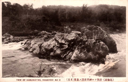 This black-and-white card shows a rocky river scene with fast-moving water and wooded banks. On the card is printed “VIEW OF KAMUIKOTAN, HOKKAIDO NO 3” and “（北海道）壯快ナル神居古潭ノ真景（其三）”. The Japanese translates as “True view of the magnificent Kamui Kotan, Hokkaido (No. 3).”