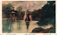 This coloured card shows a pond with a fountain surrounded by trees and garden plantings. On the card is printed “Hibiya Park Tokyo”, “日比谷公園の噴水” and “（東京名所）”. The Japanese translates as:
日比谷公園の噴水 — “The fountain in Hibiya Park”
東京名所 — “Famous places of Tokyo” / “Tokyo sights”