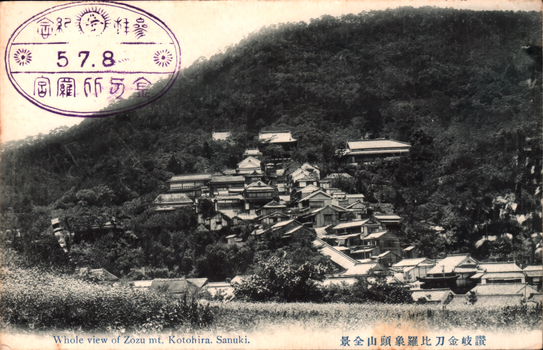 This black-and-white card shows buildings extending up a wooded mountainside. On the card is printed “Whole view of Zozu mt. Kotohira, Sanuki.” and “讃岐金刀比羅象頭山全景”. The Japanese 讃岐金刀比羅象頭山全景 translates as “Complete view of Mount Zōzu at Kotohira, Sanuki.” The purple stamp also contains “参拝記念”, “金刀比羅宮” and “5.7.8”. The Japanese translates as:
参拝記念 — “Commemorative visit to the shrine”
金刀比羅宮 — “Kotohira-gū Shrine”