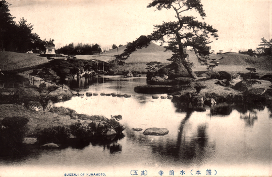 This black-and-white card shows a landscaped garden with a pond, rocks, trees and a small bridge. On the card is printed “SUIZENJI OF KUMAMOTO.” and “（熊本）水前寺（其五）”. The Japanese translates as:
熊本 — “Kumamoto”
水前寺 — “Suizenji”
其五 — “No. 5” / “Part Five”
