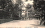 This black-and-white card shows a torii gate on a tree-lined approach with rows of stone lanterns and several pedestrians. On the card is printed “THE TOSHOGU SHRINE AT UENO PARK TOKYO.”, “上野公園東照宮” and “（東京百景）”. The Japanese translates as:
上野公園東照宮 — “Tōshōgū Shrine in Ueno Park”
東京百景 — “Hundred Views of Tokyo”