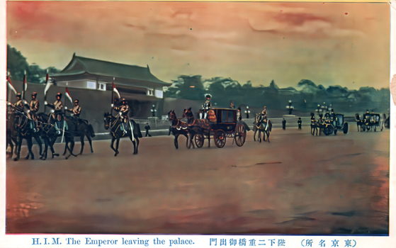 This coloured card shows the Emperor’s horse-drawn carriage and mounted escort leaving a palace precinct. On the card is printed “H. I. M. The Emperor leaving the palace.”, “陛下二重橋御出門” and “（東京名所）”. The Japanese translates as:
陛下二重橋御出門 — “His Majesty leaving through Nijūbashi”
東京名所 — “Famous places of Tokyo” / “Tokyo sights”