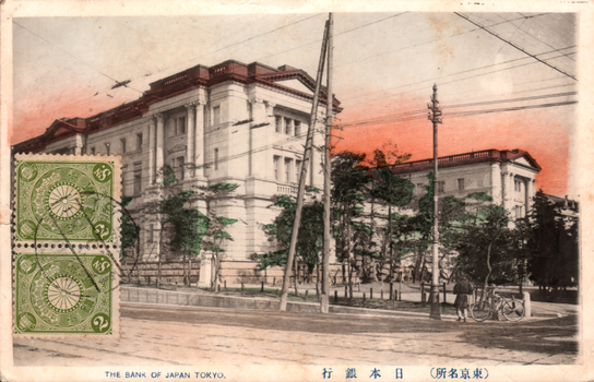 This coloured card shows the Bank of Japan building beside a street. On the card is printed “THE BANK OF JAPAN TOKYO.”, “日本銀行” and “（東京名所）”. The Japanese translates as:
日本銀行 — “Bank of Japan”
東京名所 — “Famous places of Tokyo” / “Tokyo sights”
