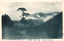 This black-and-white card shows a misty mountain landscape with a tall tree in the foreground. On the card is printed “Morning Fog Of Kogmaatake” and “木曾名勝　駒ヶ嶽ノ朝霧”. The Japanese translates in English as “Morning mist of Mount Komagatake, a famous scenic place in Kiso.”