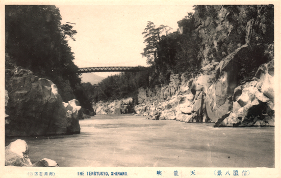 This black-and-white card shows a river gorge with steep rocky cliffs and a bridge in the distance. On the card is printed “THE TENRYUKYO, SHINANO.”, “天龍峽”, “（信濃八景）” and “（河原書店版）”. The Japanese translates as:
天龍峽 — “Tenryū Gorge”
信濃八景 — “Eight Views of Shinano”
河原書店版 — “Kawahara Bookshop edition”