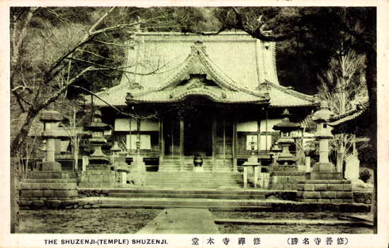 This black-and-white card shows the main temple building at Shuzenji, with stone lanterns in front. On the card is printed “THE SHUZENJI-(TEMPLE) SHUZENJI.”, “修善寺本堂” and “（修善寺名勝）”. The Japanese translates as:
修善寺本堂 — “Main hall of Shuzenji Temple”
修善寺名勝 — “Famous sights of Shuzenji”