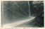 This black-and-white card shows a suspension bridge crossing a wooded ravine, with two people standing on the bridge. On the card is printed “View of Suspense Bridge Yamanaka at kiso”, “山中の釣橋” and “（木曾名所）”. The Japanese translates as:
山中の釣橋 — “Suspension bridge at Yamanaka”
木曾名所 — “Famous sights of Kiso”