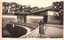 This black-and-white card shows the Sakuradamon Gate and stone walls beside a bridge, with bicycles in the foreground. The English caption is partly obscured; the clearly readable portion is “…Sakuradamon Gate Tokyo”. On the card is also printed “皇居櫻田門” and “（東京名所）”. The Japanese translates as:
皇居櫻田門 — “Sakuradamon Gate of the Imperial Palace”
東京名所 — “Famous places of Tokyo”