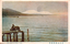 11731.200 This coloured card shows a snow-covered mountain range across a body of water, with two figures on a wooden platform in the foreground. On the card is printed “The Snow at Hira, Oumi.” and “近江比良峯暮雪”. The Japanese 近江比良峯暮雪 translates as “Evening snow on Mount Hira, Ōmi.”