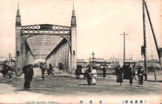 This black-and-white card shows a large iron bridge with pedestrians and vehicles. On the card is printed “AZUMA BLIDGE TOKYO”, “吾妻橋” and “（東京名所）”. The Japanese translates as:
吾妻橋 — “Azuma Bridge”
東京名所 — “Famous places of Tokyo” / “Tokyo sights”