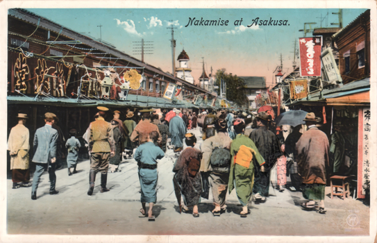 This coloured card shows a crowded shopping street at Asakusa, with shops and signs on both sides. On the card is printed “Nakamise at Asakusa.” There is no separate printed Japanese caption along the border. A vertical shop sign at the right reads “寿司”, meaning “sushi.”