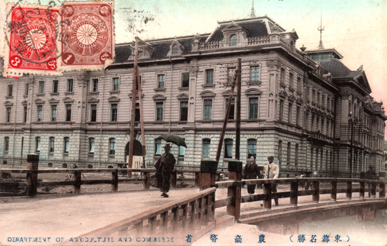 This coloured card shows a large Western-style government building viewed from a bridge, with pedestrians in the foreground. On the card is printed “DEPARTMENT OF AGRICULTURE AND COMMERCE.” and “（東京名勝）農商務省”. Japanese translation:
（東京名勝）農商務省 — “(Famous sight of Tokyo) Ministry of Agriculture and Commerce.”
東京名勝 — “Famous sight of Tokyo”
農商務省 — “Ministry of Agriculture and Commerce”