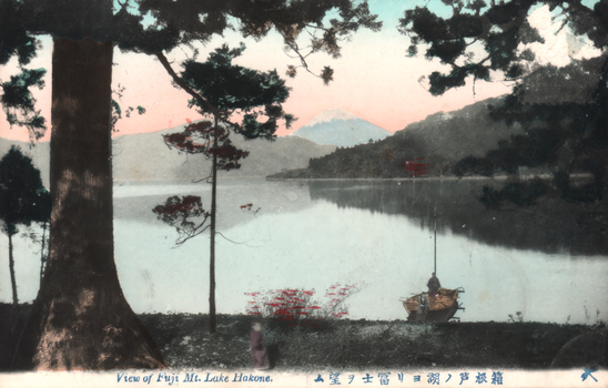 This coloured card shows a lakeside view with trees in the foreground, a small boat on the shore, and Mount Fuji in the distance. On the card is printed “View of Fuji Mt. Lake Hakone.” and “箱根芦ノ湖ヨリ富士ヲ望ム”. Japanese translation: 箱根芦ノ湖ヨリ富士ヲ望ム — “View of Mount Fuji from Lake Ashi, Hakone.”