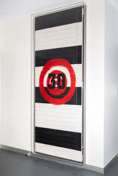 A large painting with black and white alternating colour blocks and a red target with the number 30.