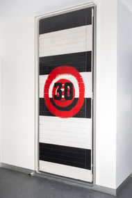 A large painting with black and white alternating colour blocks and a red target with the number 30.