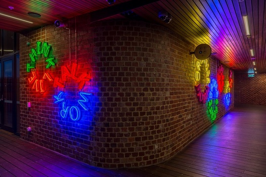 Colourful neon text-based artwork installed on red brick walls.
