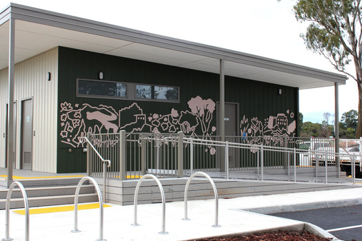 A sports pavilion painted dark green on one wall featuring bold outlines in dusty pink that depict various plants, trees, hills and buildings. 