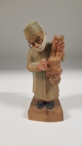 Sculpture - Carved wooden figurine of a doctor holding a baby