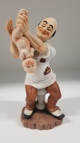 Sculpture - Porcelain figurine of an obstetrician holding a baby
