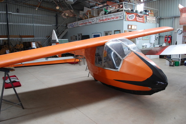 Orange and Black glider fuselage with wing centre section in hangar