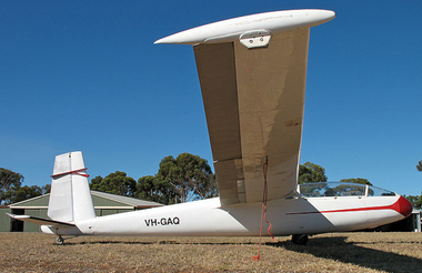 SIde view of a white glider on a grassy airfield