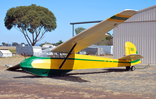 Green Yellow and white glider at rest outside workshop