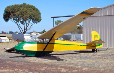 Green Yellow and white glider at rest outside workshop