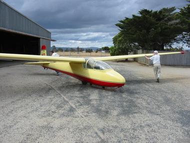 Cream and red glider being pushed back into a hangar