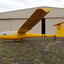 Yellow glider at rest in front of hangar