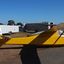 Yellow and white glider at rest near several glider trailers