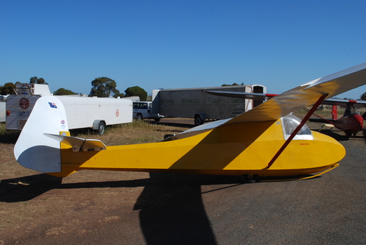 Yellow and white glider at rest near several glider trailers