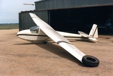 Glider at rest in front of hangar