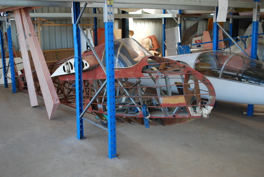 Wooden glider fuselage stripped of fabric covering in hangar