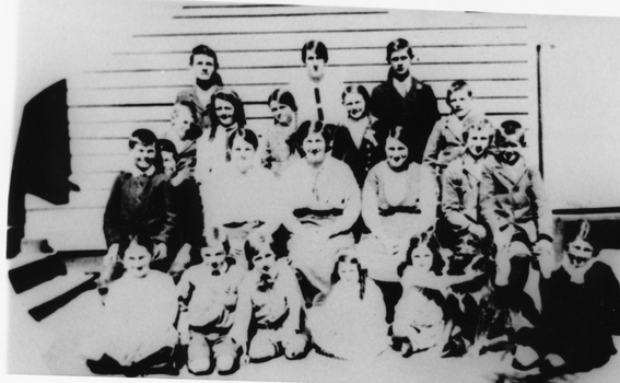 Students assembled outside the Yeungroon East State School. A group of 22 children of variou ages in front of a weather board building.