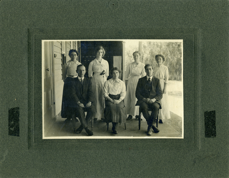 Charlton Higher Elementary School teachers seated on veranda of Charlton Higher Elementary School. Seven teachers, two male, five female seated and standing.