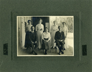 Charlton Higher Elementary School teachers seated on veranda of Charlton Higher Elementary School. Seven teachers, two male, five female seated and standing.